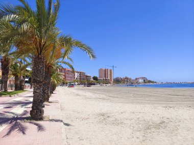San Javier, Murcia, İspanya - 10 Haziran 2022. La Manga del Mar Menor sahilinde palmiye ağaçlı turistler. Akdeniz 'de güneşli bir gün..