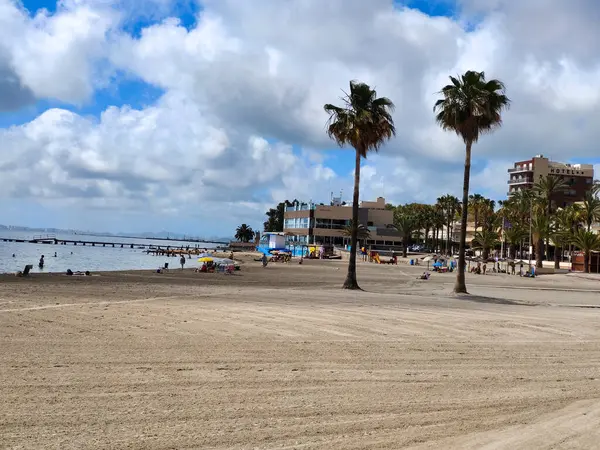 San Javier, Murcia, İspanya - 10 Haziran 2022. La Manga del Mar Menor sahilinde palmiye ağaçlı turistler. Akdeniz 'de güneşli bir gün..