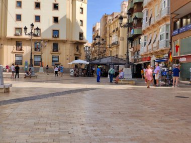 Cartagena, İspanya-13 Haziran 2022 - İspanya 'nın güneyindeki Kartagena sokakları güneşli bir günde. Kıyı şehrinde gezinen insanları ve tipik mimariyi görebilirsiniz..