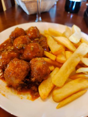 Tabakta servis edilen kızarmış patatesli köfte.