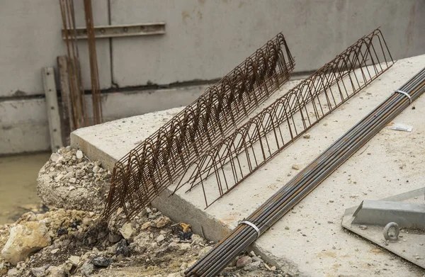 a bundle of steel rods and reinforcing steel elements on a concrete floor of a construction site