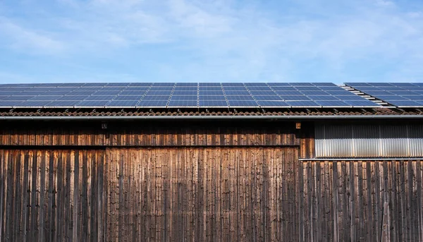 a wooden barn in the country with solar panels installed on the roof