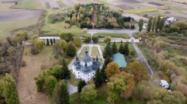 Drone footage of trees in autumn and church in the park. Fly over the park, yellow, green and red trees, church and cathedral in the park - drone view 4k