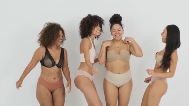 グレーを背景に身体のポジティブなコンセプトを表現しながら 下着姿の多民族女性たちが楽しそうに笑顔で踊る様子 — ストック動画