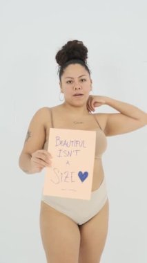 İç çamaşırlı, dövmeli ve piercingli mutlu bir kadın modelin statik çekimi. Gri arka planda zarif bir şekilde dans eden bir beden ölçüsü güzel değil.