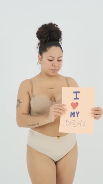 Vücudumu Seviyorum Posterini Gösteren Kameraya Konuşan Gri Arka Planda Gülümseyen — Stok video