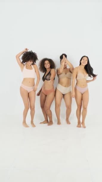 雄々しいショットの陽気な多人種間の女性の友人で下着で異なるボディタイプの笑いとダンス一緒にグレーの背景 — ストック動画