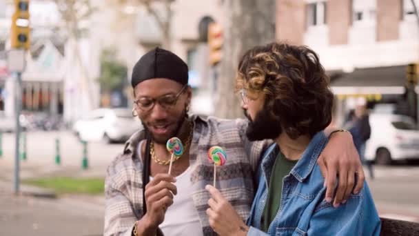 Çok Kültürlü Eşcinsel Bir Çiftin Lolipop Yerken Kenarda Oturup Sohbet — Stok video
