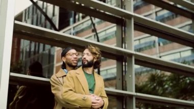 Çok kültürlü homoseksüel bir çiftin şehir caddesinde konuşurken kucaklaşmasını gösteren düşük açılı bir video.