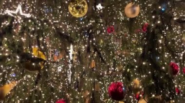Gece aydınlatılmış mücevherler ve ışıklarla süslenmiş bir noel ağacının yolculuğuyla ilgili video.