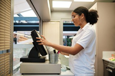 Afro-Afrikalı bir tezgahtar profili bir kafeteryada kasayı kullanıyor.