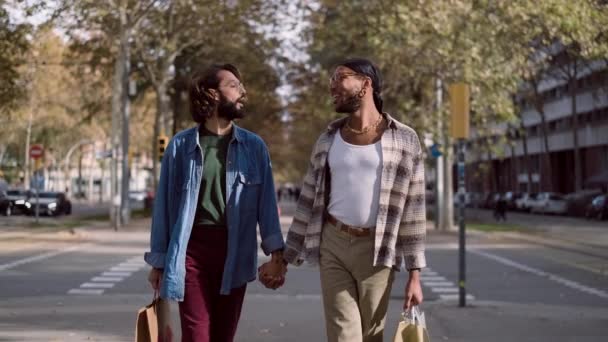 低速の動きビデオの同性愛者のカップル歩くとともに通りに沿って紙のショッピングバッグ — ストック動画