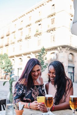 Bira içen ve cep telefonunu barda kullanan çok ırklı arkadaşların fotokopi alanı olan dikey fotoğraf.