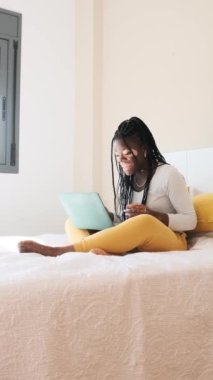 Yavaş çekim dikey videosu Vitiligo 'lu siyahi bir kadının online bir toplantı sırasında yatakta el kol hareketi yapması.