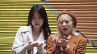 Konfetiden önce gülümseyen Asyalı lezbiyen bir çiftin yavaş çekim videosu.