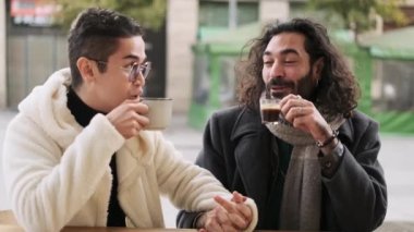 Kafeteryada kahve içerken konuşan şık bir gay çiftin yavaş çekim videosu.