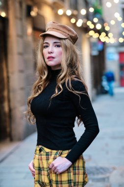 Sokakta kameraya bakarken poz veren seksi sarışın bir kadının dikey portresi.