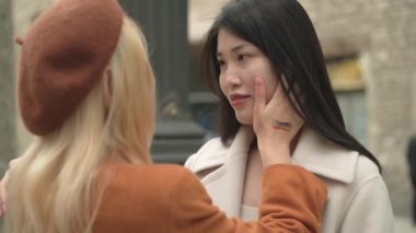 İki Asyalı lezbiyen kadının caddede yan yana oturduğu bir sahnenin yavaş çekim videosu.