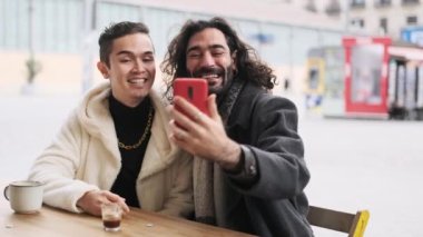 Açık hava kafeteryasında somurtup selfie çeken havalı ve mutlu bir çiftin yavaş çekim videosu.