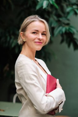 Businesswoman looking at camera and smiling while standing outdoors. Business and success concept.