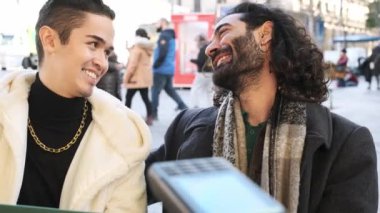 Slow motion video of a happy gay couple paying with a credit card at a payment terminal