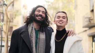 Slow motion video of a cool gay couple walking while embracing in the street