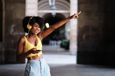 Young woman with eyes closed dancing relaxed while listening music with headphones outdoors. Technology concept.