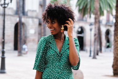 Happy woman looking away and smiling while standing outdoors on the street.