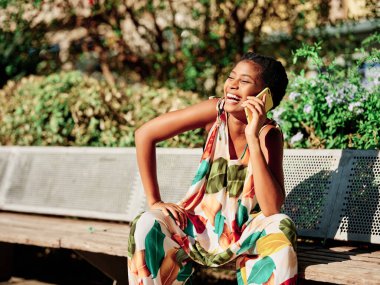 Parkta telefonda konuşurken gülümseyen neşeli bir kadın. Teknoloji konsepti.