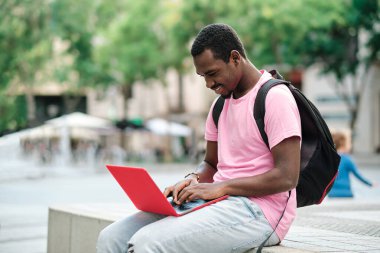 Man with backpack using a laptop outdoors. Technology concept.
