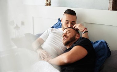Male gay couple relaxing in bed together at home. Lgbt concept.