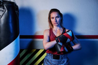 Female boxer putting on her boxing gloves while training in the gym. Sports concept.