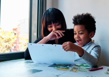 Ev ödevini yapan Latin bir anne ve oğlun portresi. Evdeki bir masada oturuyor.