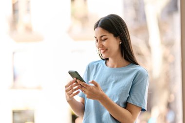 İspanyol kadın dışarıda cep telefonu kullanırken gülümsüyor.