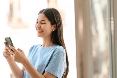 İspanyol mutlu kadın dışarıda cep telefonu kullanırken gülüyor