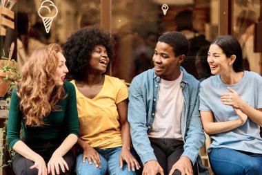 Sokakta otururken gülümseyen mutlu çoklu etnik arkadaşlar