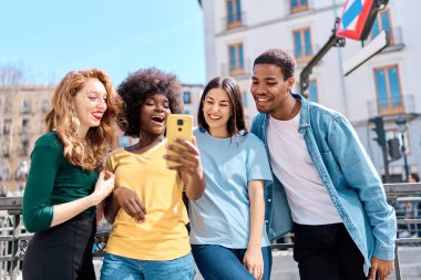Şehre giderken cep telefonu kullanan çok ırklı arkadaş grubu