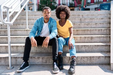 Sokakta merdivenlerde oturan Afrikalı şık arkadaşların ön portresi.