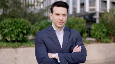 Kollarını açık havada açarak gururla duran gülen bir iş adamının yavaş çekim videosu.