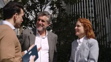 Bir finans binasının önünde gevşeyen üç iş adamının yavaş çekim videosu