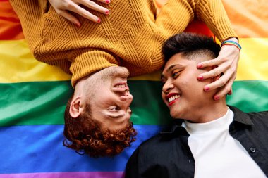 Igtb gökkuşağı bayrağında uzanan eşcinsel bir çiftin hassas bir sahnesinin en üst görüntüsü.