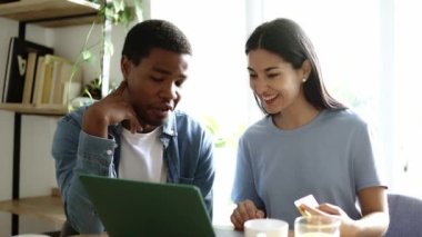 Evde online alışveriş yapan iki farklı etnik arkadaşın yavaş çekim videosu.