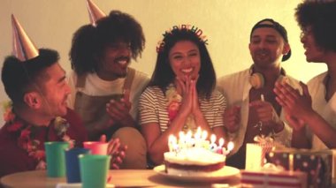 Mutlu bir kadının arkadaşlarıyla doğum günü pastasının mumlarını üflediği yavaş çekim videosu.