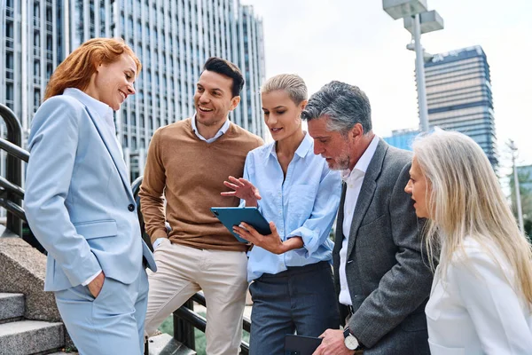 stock image Group of business people using a tablet standing in the city street