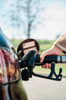 Ekonomik ve petrol krizleri sırasında el yakıtını arabasıyla dolduran bir kadının dikey fotoğrafı
