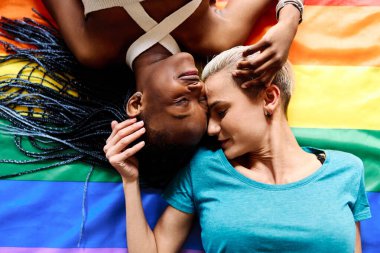 Lgtb gökkuşağı bayrağının üzerinde yatan lezbiyen bir çiftin üst görünüm portresi