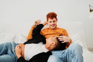 Evdeki kanepede rahatlamış, çok ırklı eşcinsel bir çiftin romantik bir sahnesinin ön görüntüsü.