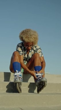 Dışarıda paten bağlayan Afrikalı bir kadının dikey videosu.