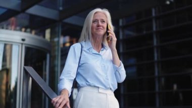 Olgun bir iş kadınının finans bölgesindeki bir telefon görüşmesinde yörüngeye oturması