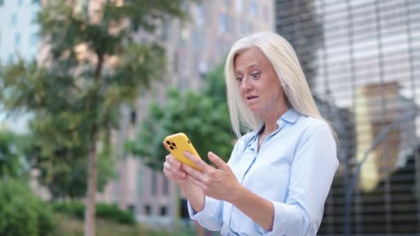 Седовласая Профессиональная Женщина Наслаждается Социальными Клипами Среди Городской Зелени Небоскребов — стоковое видео